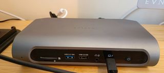 A grey Satechi Thunderbolt 4 dock sitting on a wooden desk