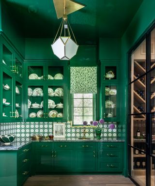 dark green butler's pantry with green and white backsplash and gold pendant light