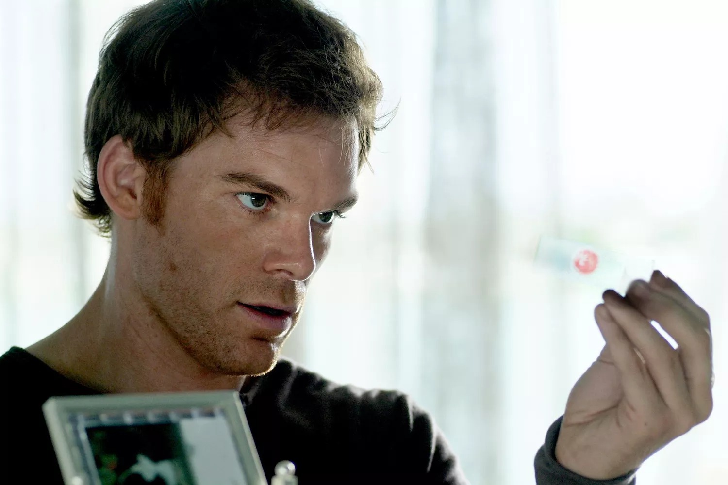 Michael C. Hall stars as &#039;Dexter&#039; wearing gloves and investigating a crime scene in a still from the detective series