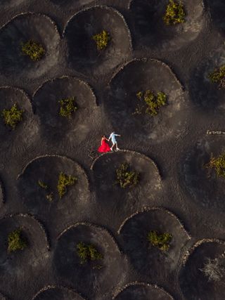 An aerial view of a couple pretending to walk over a hump-shaped wall