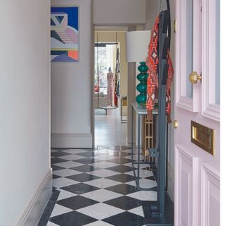 Hallway with monochrome tiles and a pink front door