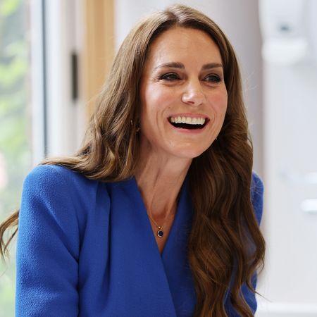 Princess Kate wears a blue wrap dress and has long wavy brown hair