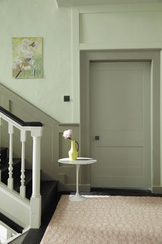 A sage green staircasen wall with white balustrade