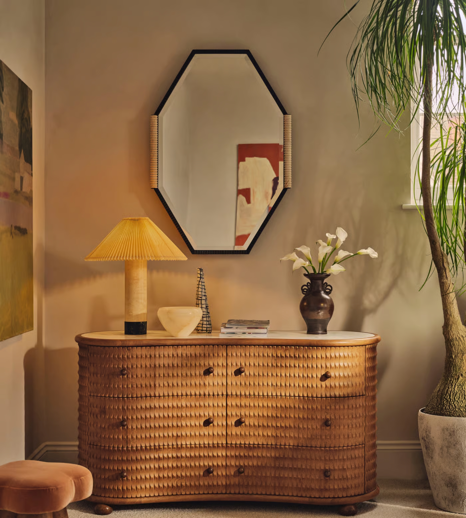 a textured dresser with a marble top with a lamp on and an octagonal mirror