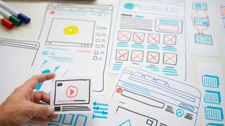 person working on hand-drawn website design documents