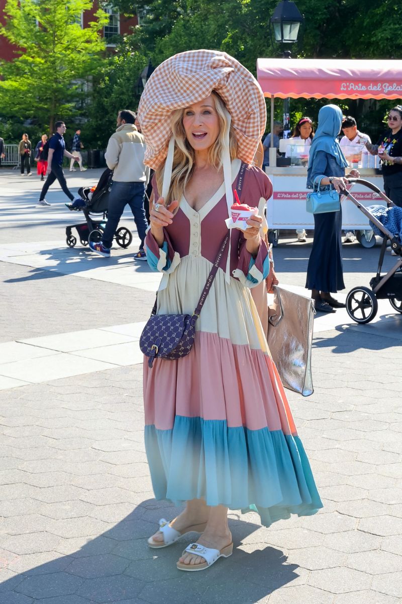 Sarah Jessica Parker on set for And Just Like That wearing a giant checked hat and white Dr Scholl's clogs