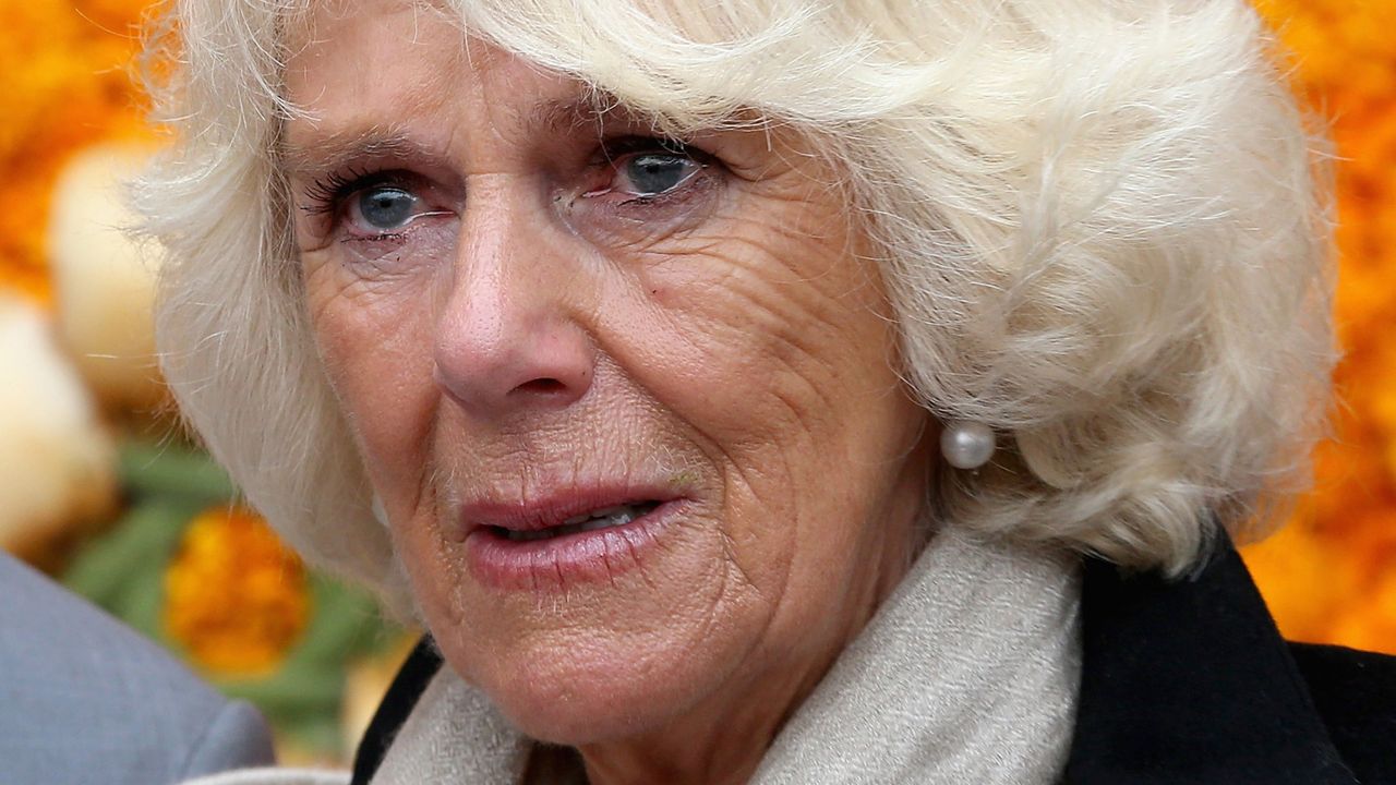 Queen Camilla has blonde coiffed hair and has tears in her eyes