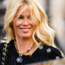 Claudia Schiffer wearing a black jacket smiling, with the wind in her blonde hair demonstrating hair colours for the over 50s