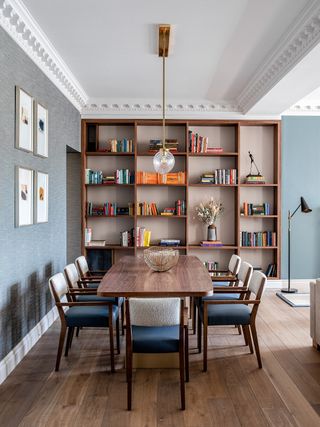 Grey backed, wooden bookshelf, wooden dining table, blue and white dining chairs