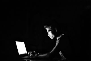 man sat at laptop in dark room