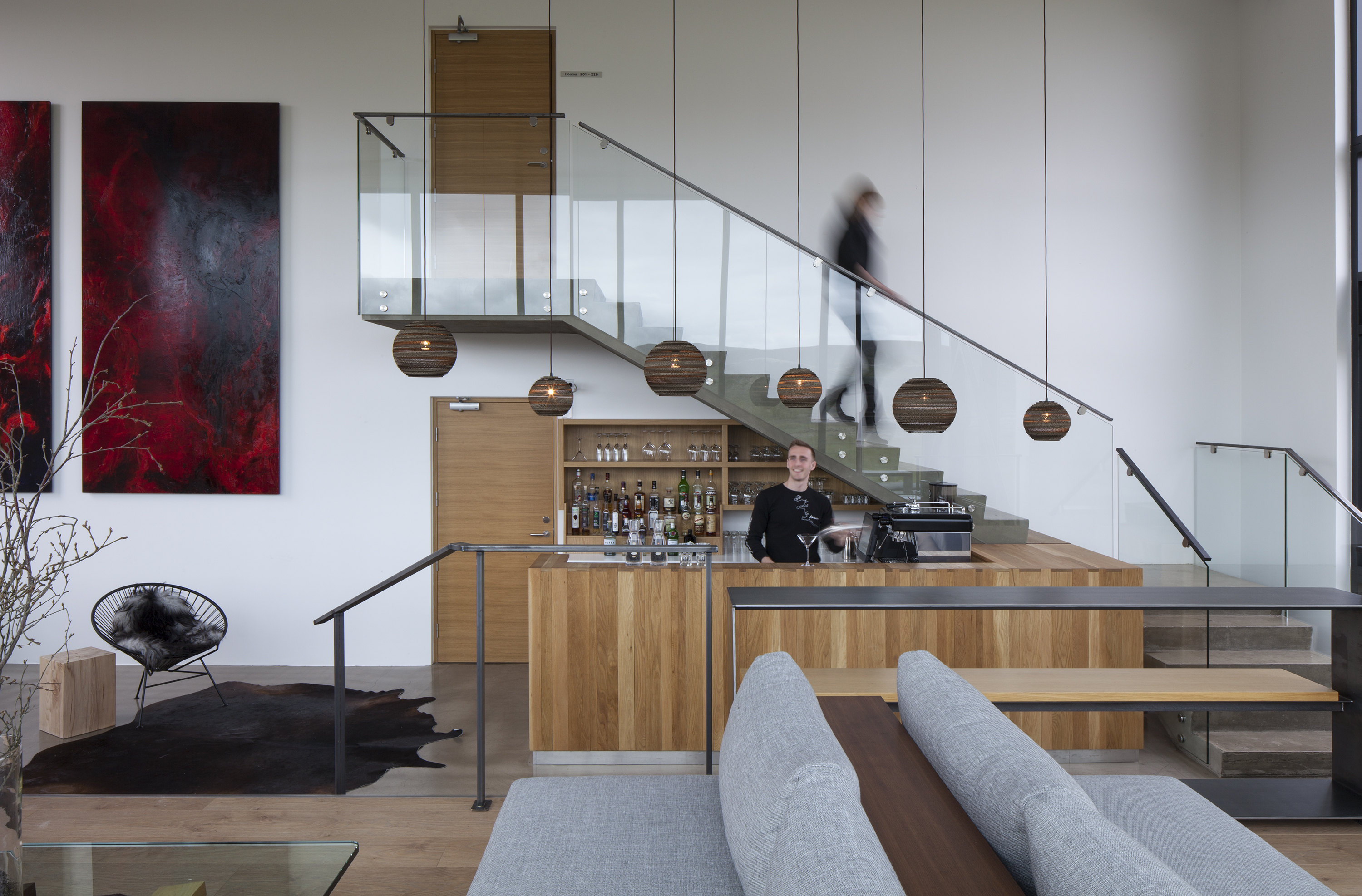 A hotel is nestled atop rocky formations in an Icelandic desert landscape, with floor-to-ceiling windows and minimal furnishings letting the outdoors in.