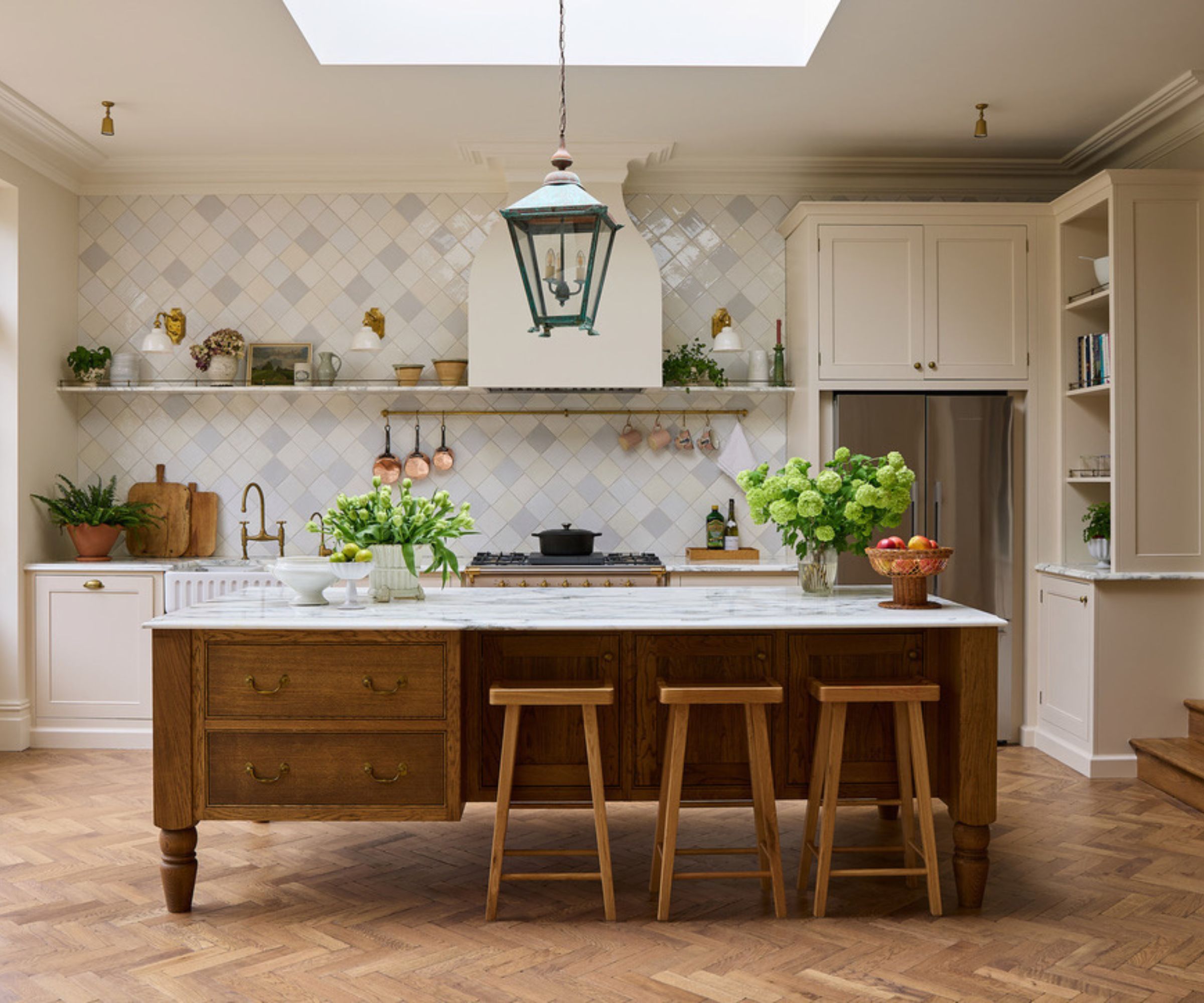A neutral kitchen with a large wooden kitchen island housing storage and seating space