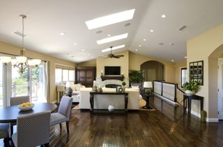 Living space with vaulted ceiling, dining table and chairs, living area, wood floor, neutral walls and white ceiling