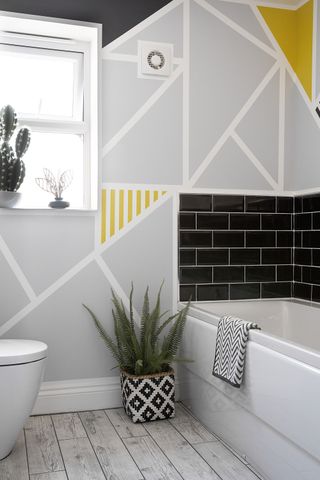A modern bathroom idea featuring a geometric paint effect on walls in grey, white and yellow