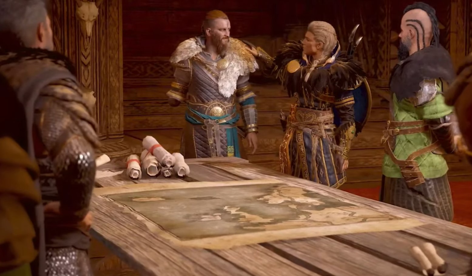 Eivor clasping the shoulder of a one armed man while overlooking a campaign map in the middle of a mead hall.