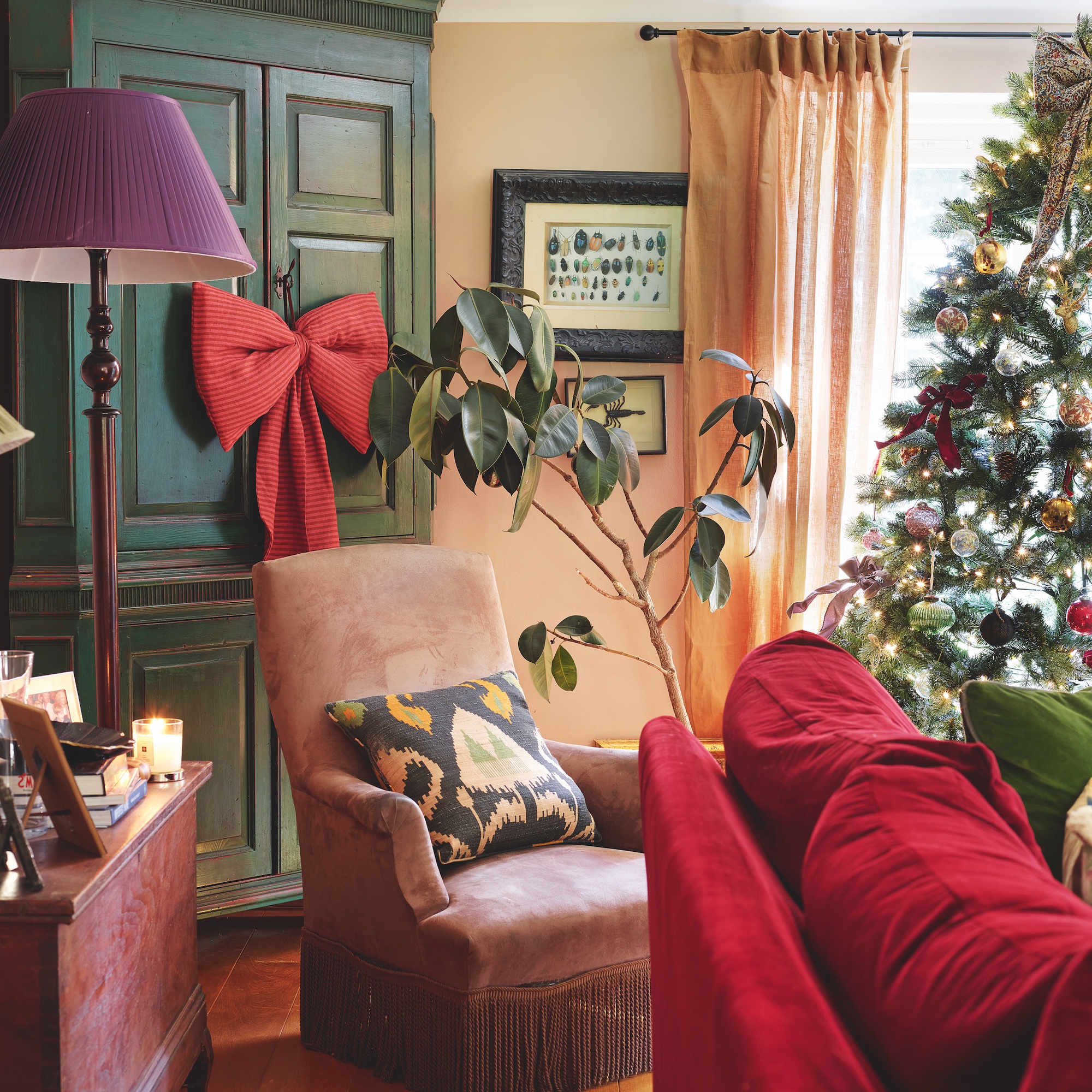 sitting room with pink occasional chair and red sofa, with green corner cabinet decorated with large red fabric bow
