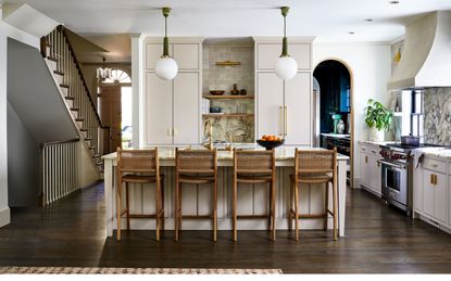 cream colored kitchen with island, wooden chairs and floors