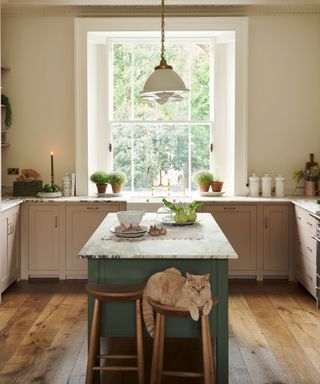 A pink kitchen with marble countertops and a green island