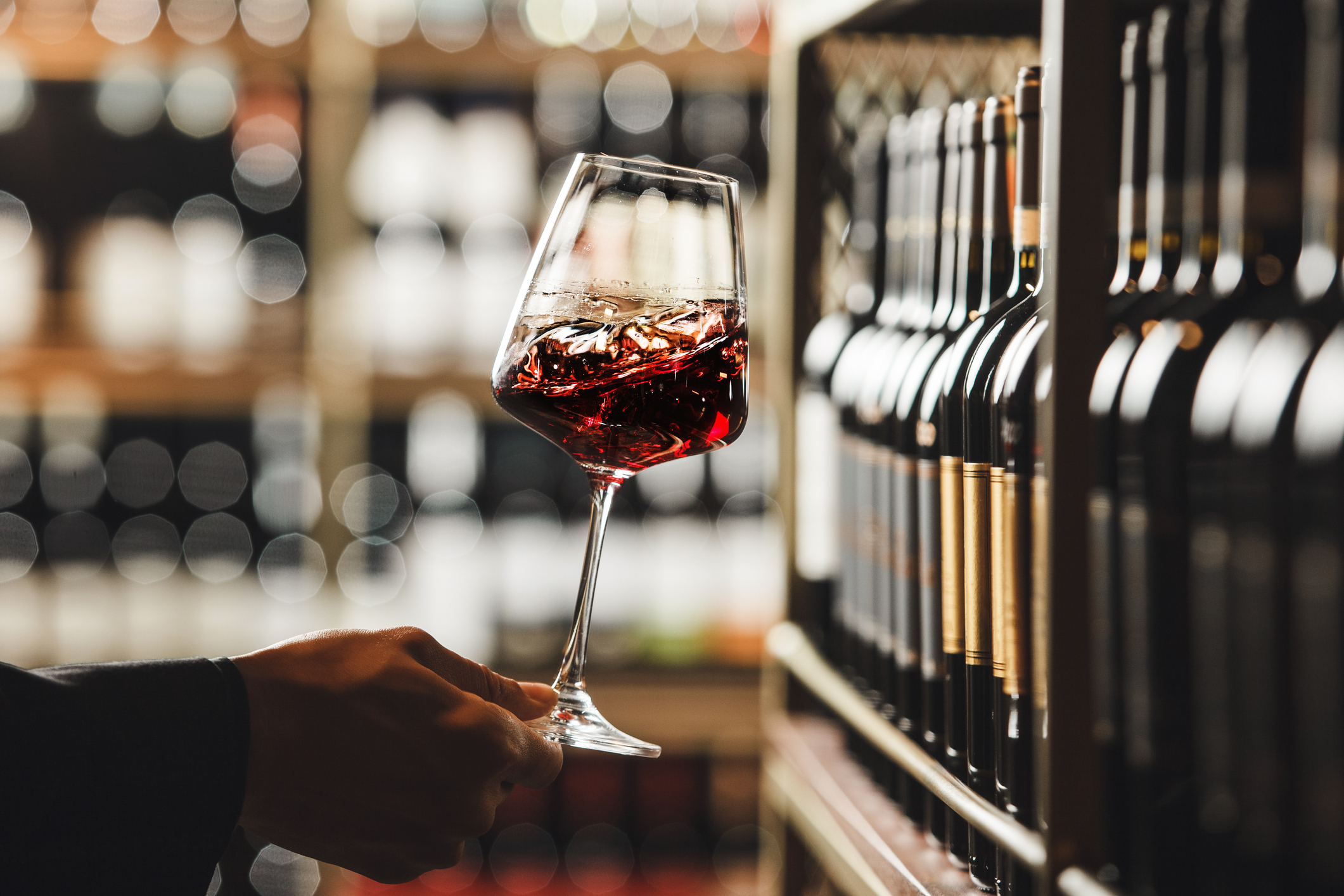 Close up shot of person hand as they swirl a glass of red wine