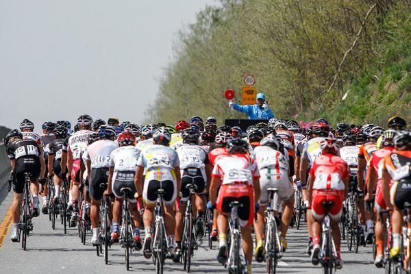 The peloton rolls out out from the start line in the neutral zone, awaiting the go ahead to commence racing.