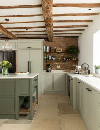 exposed original wooden beams and green painted kitchen with exposed brick walls and open shelves