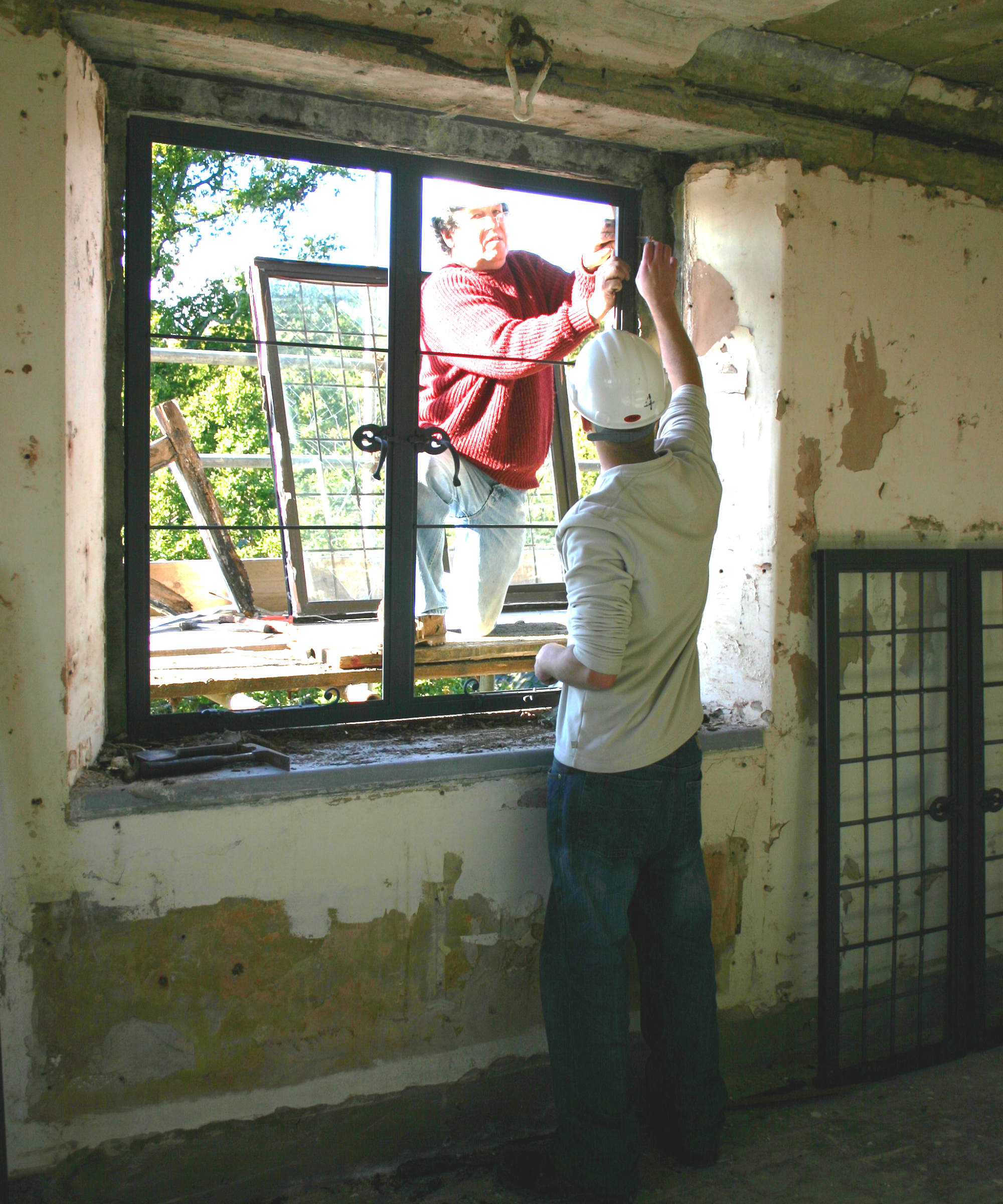 two workers replacing windows in old building