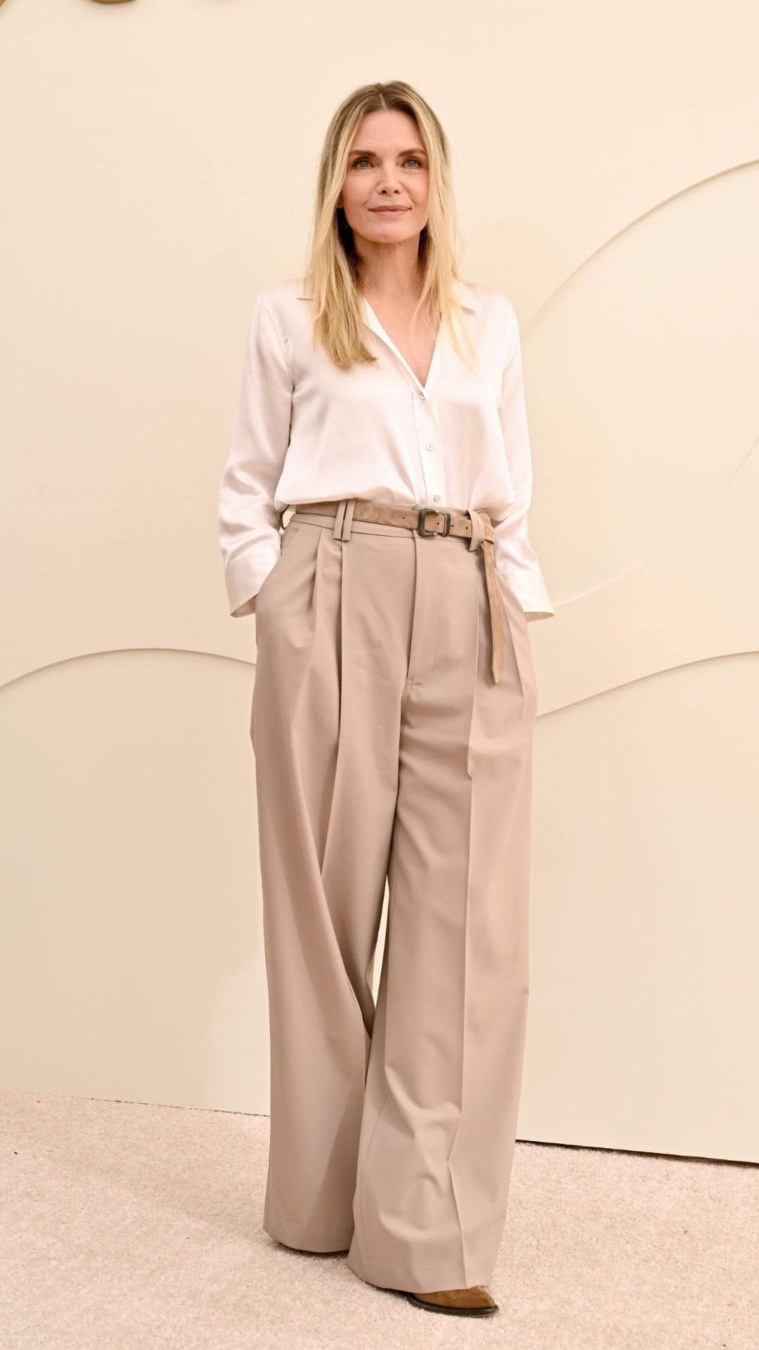 michelle pfeiffer wearing a white blouse and beige wide leg trousers