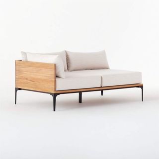 An off white CB2 left arm loveseat with teak wood, for the best outdoor furniture brands. 