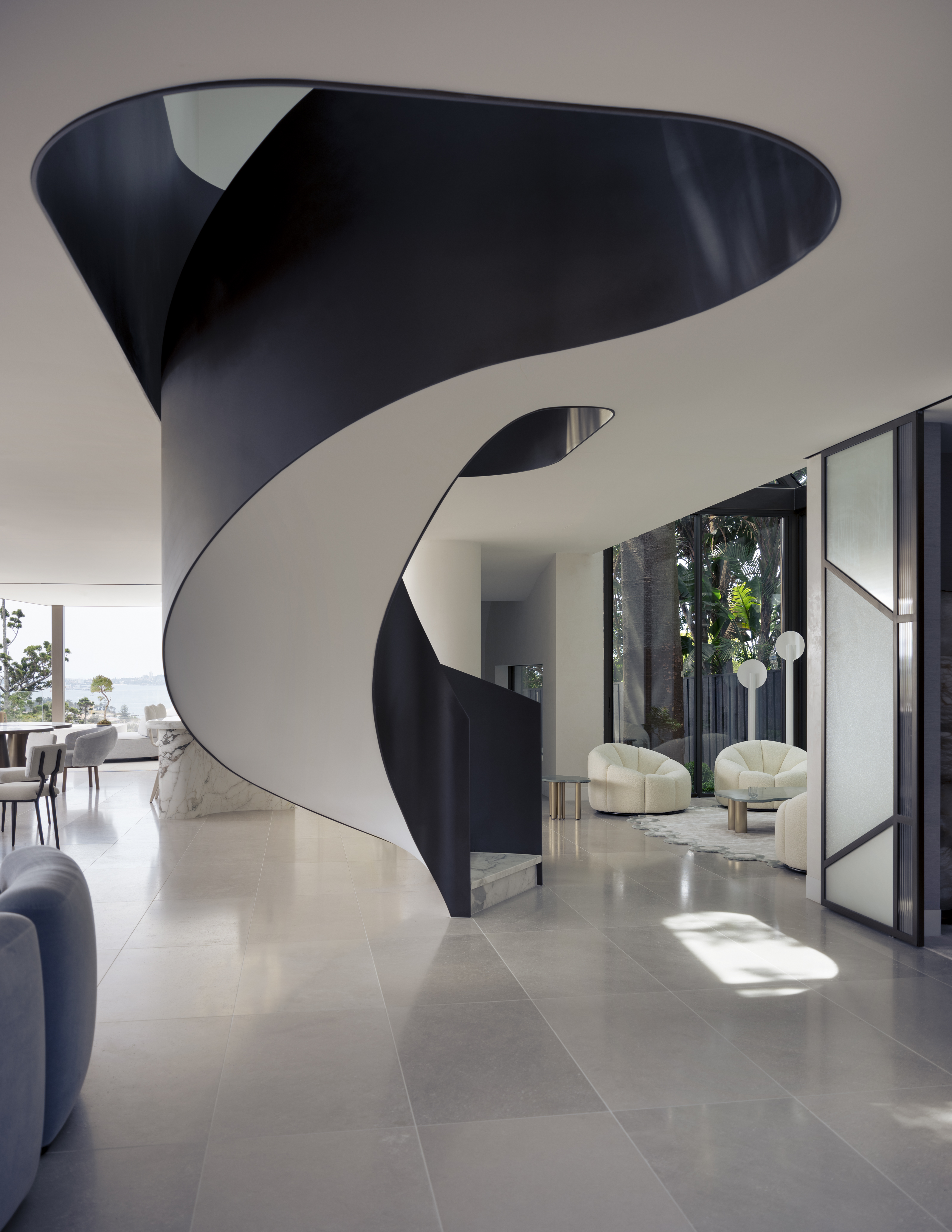 a monochrome design modern staircase curving through the centre of a modern living space