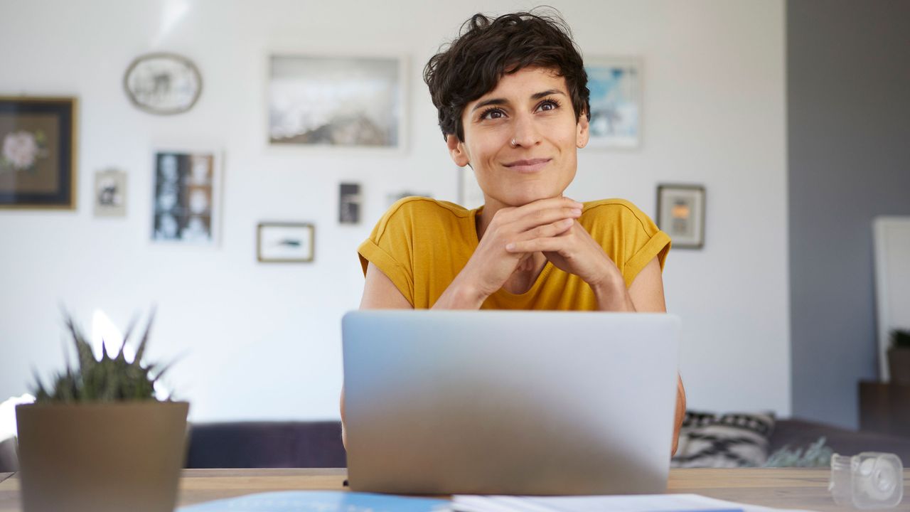 A worker sits at a laptop with a happy look on her face.