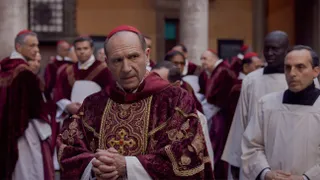 Ralph Fiennes (center front) stands among a crowd of Roman Catholic priests and cardinals in 'Conclave.'