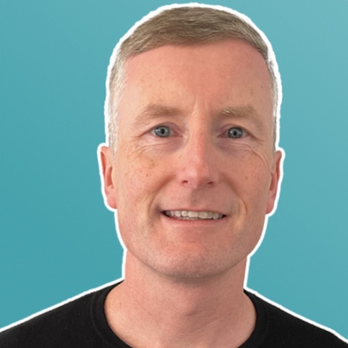 Image of a man in a black shirt in front of a teal background.