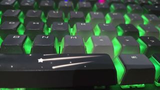 A close up on the space bar of the Cherry MX 8.2 Wireless Xaga gaming keyboard. The RGB lights are on. The space bar key features an opaque shooting star design that the RGB lights cannot shine through.