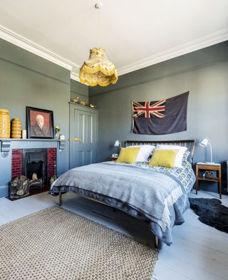 Bedroom painted in Down Pipe blue paint by Farrow and Ball with bedside table, retro chairs, large bed and rug