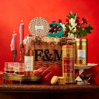 Christmas hamper with wine and food in a basket on a red background