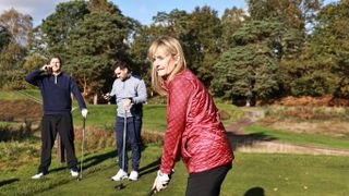 Golfer on the phone while another player is teeing off