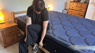 Our reviewer sitting on the edge of the DreamCloud Luxe Memory Foam mattress to assess its edge support