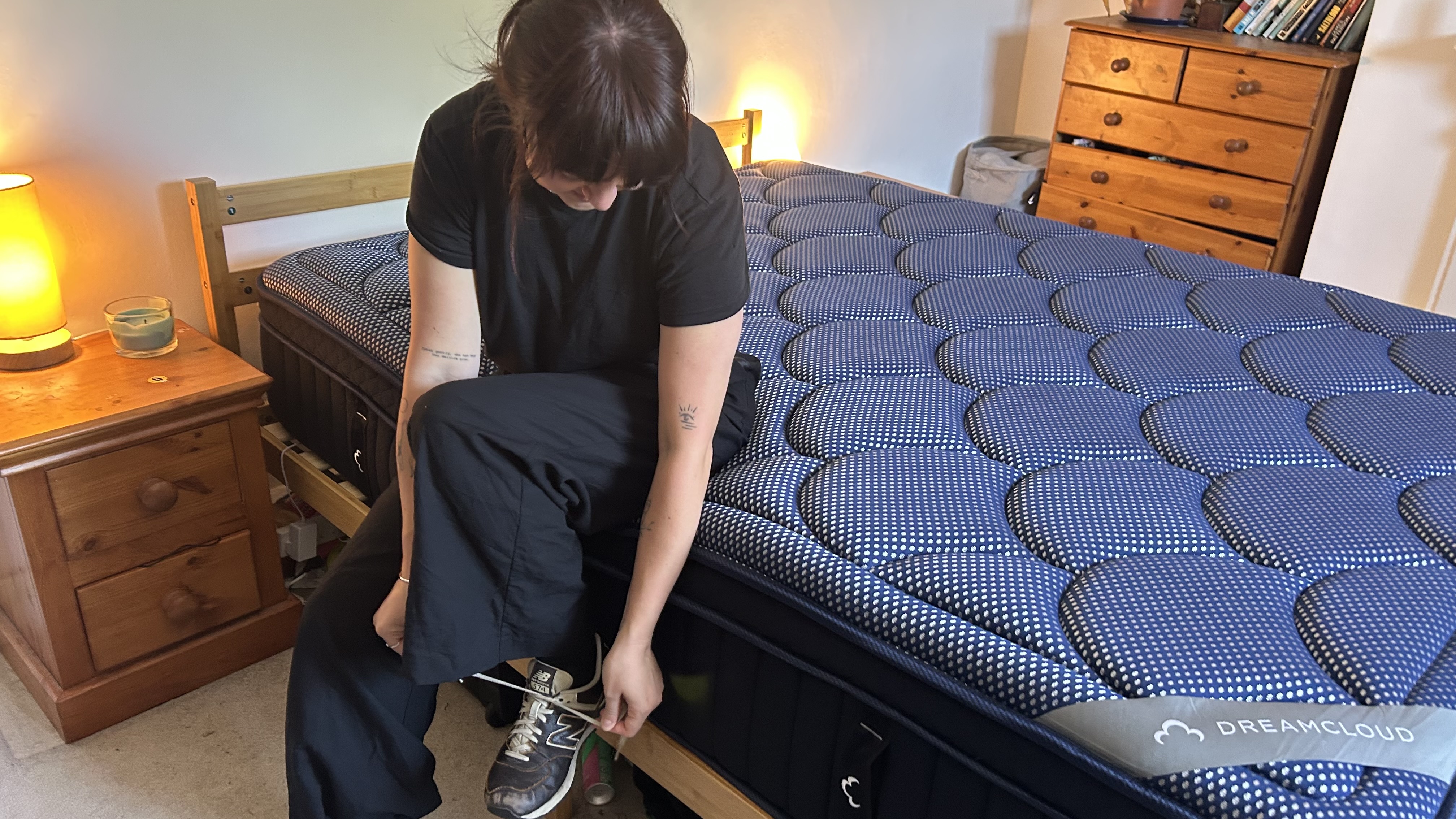 Our reviewer sitting on the edge of the DreamCloud Luxe Memory Foam mattress to assess its edge support