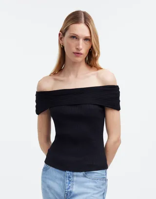 model wears off the shoulder black top and blue jeans 