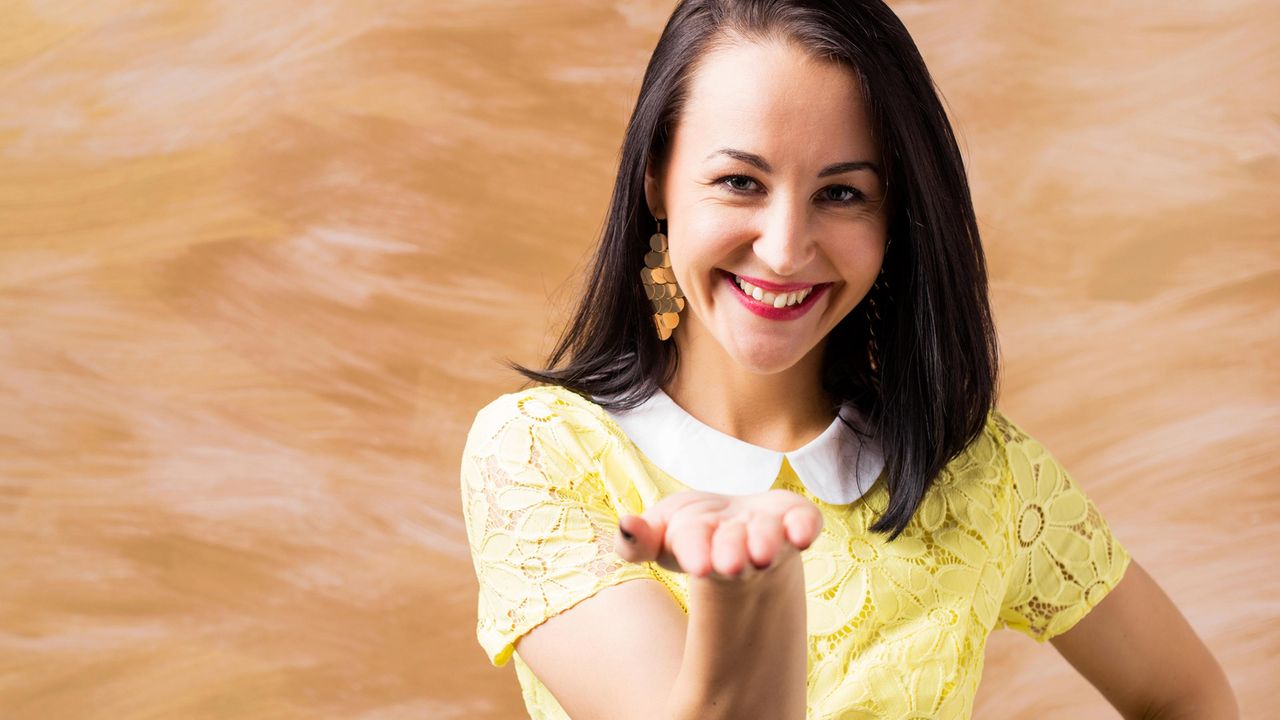 A smiling woman holds her hand out.