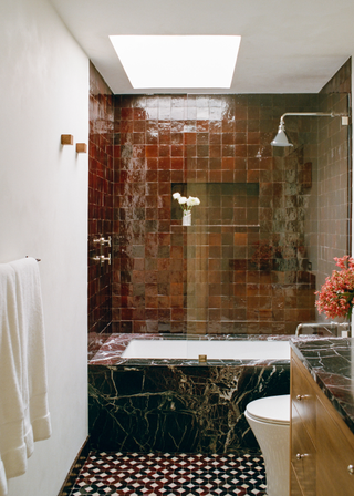 Gorgeous small bathroom with red marble bth and maroon tiled walls.