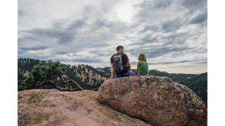 Man and woman sitting on a boulder in Rocky Mountains
