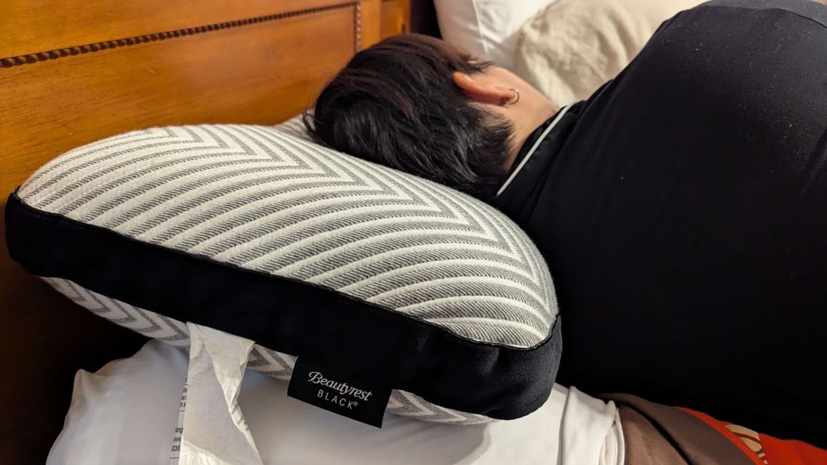 The image shows a woman sleeping on the Beautyrest Black Luxury Foam Pillow