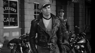 Marlon Brando in a leather biker jacket, standing in front of some motorcycles in The Wild One