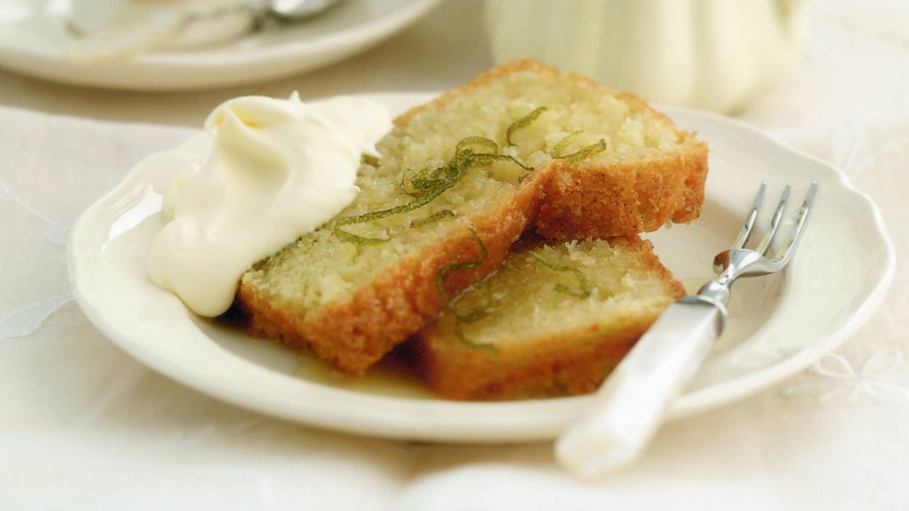 coconut and lime cake slices on a cake plate with some cream on the side