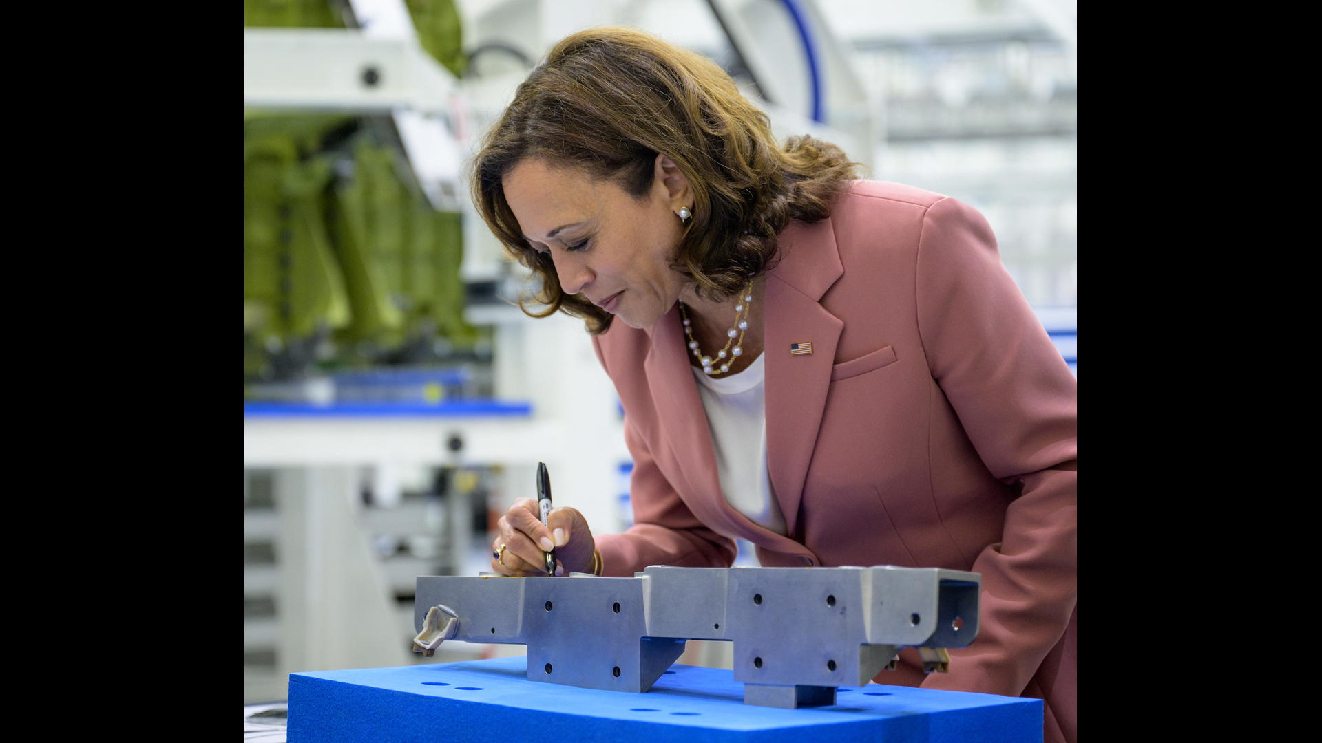 Vice President Kamala Harris signs a bracket that will fly to the moon on the Artemis 3 Orion spacecraft while touring NASA's Neil A. Armstrong Operations and Checkout Building at NASA’s Kennedy Space Center in Florida on Aug. 29, 2022.