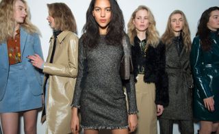 Models waiting in line for a fashion show to start, wearing: sky blue skirt and jacket, elegant leather coat in beige, with jeweled black velvet mini dress front and center, from the Topshop Unique A/W 2015 collection.