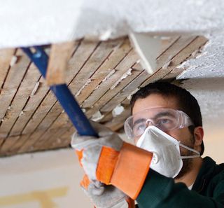 man in mask repairing ceiling