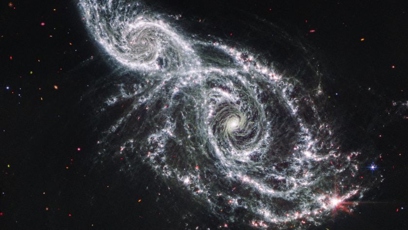 A deep space image showing the white gas and stars forming two spiral galaxies next to each other, stretching from the bottom right to top left of the image. 