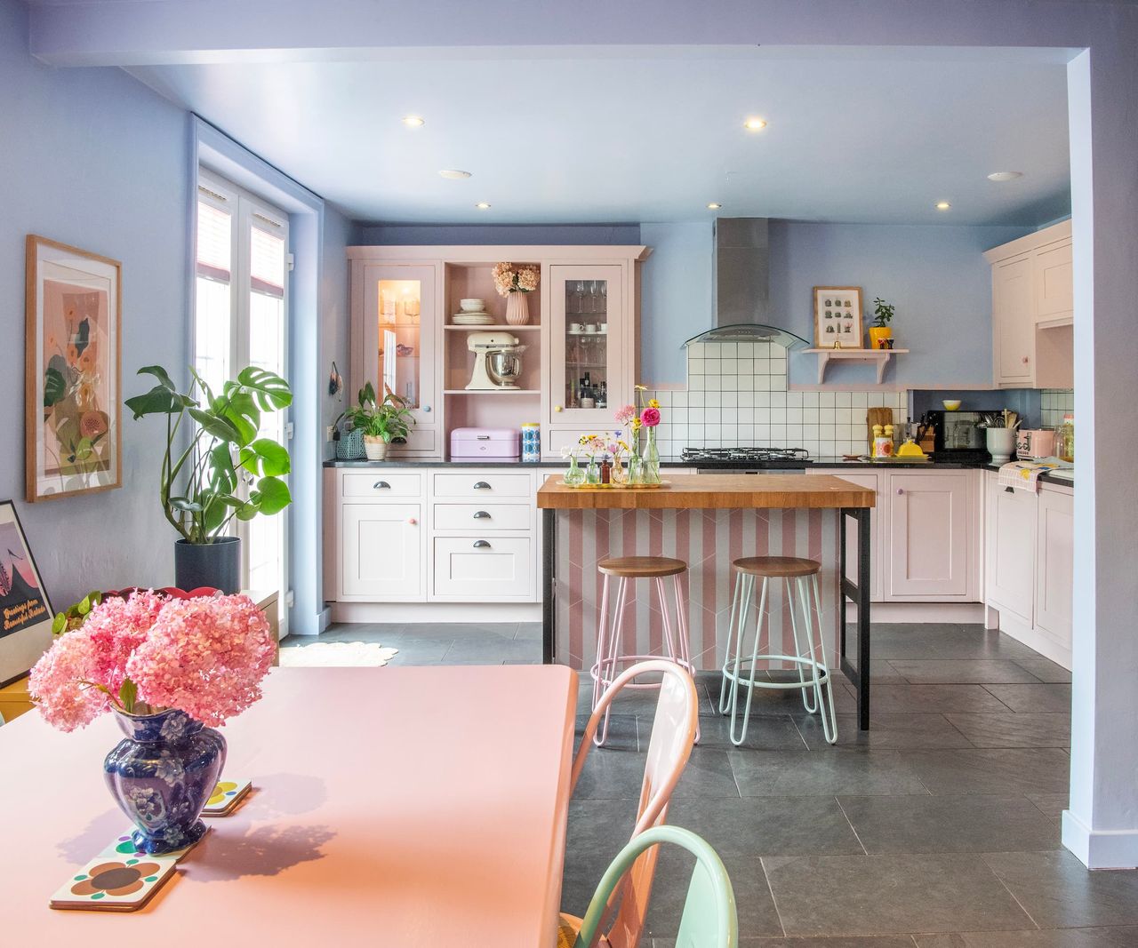 A kitchen-diner with a small wooden top kitchen island and tiled floor